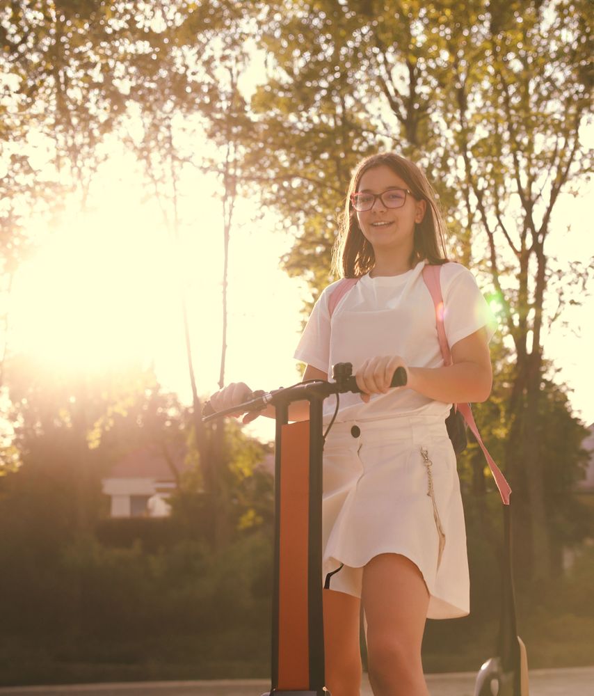 Bild på en flicka som står på en elsparkcykel.